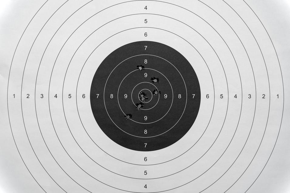 Zielscheibe mit mehreren Löchern, platziert in der Mitte der schwarzen Zone, umgeben von konzentrischen Ringen.